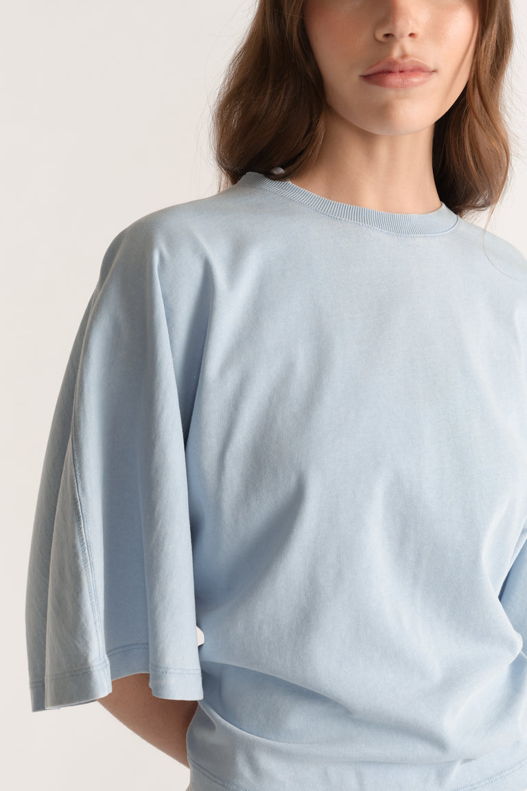 Woman wearing a relaxed light blue crew neck tee with dropped shoulders and batwing sleeves
