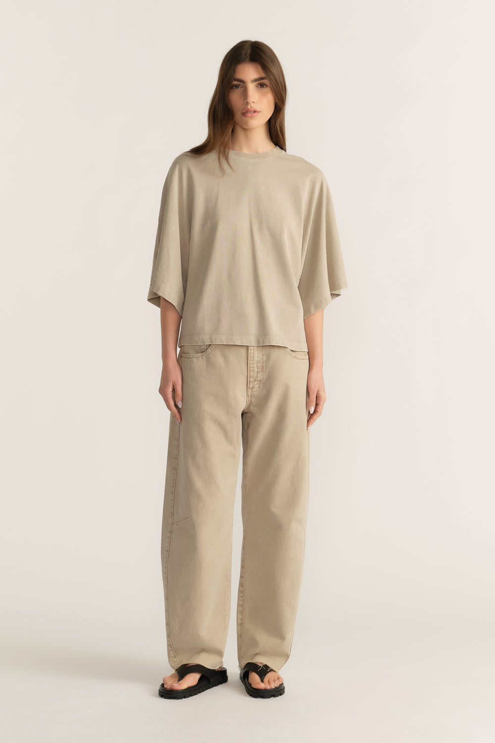 Woman wearing a relaxed beige tee with wide-leg pants and black sandals