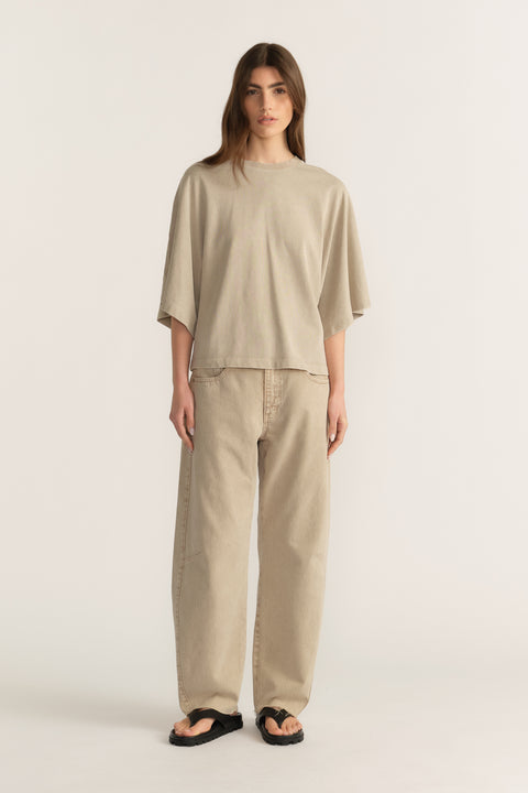 Woman wearing a relaxed beige tee with wide-leg pants and black sandals