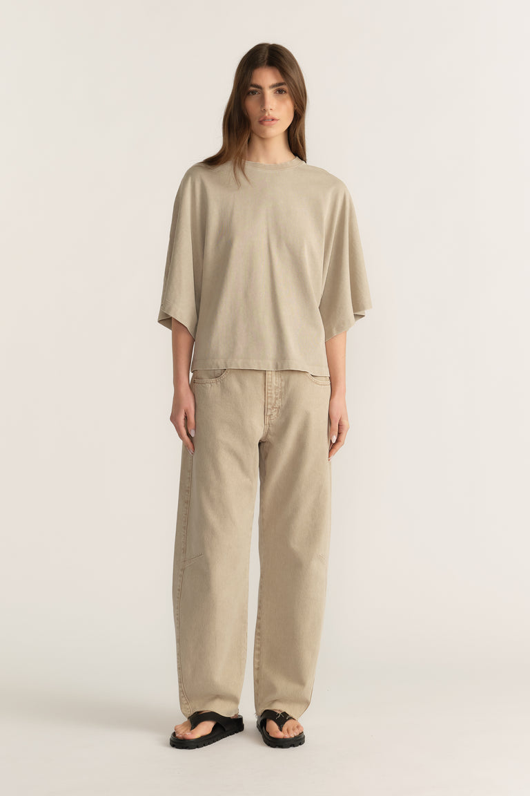 Woman wearing a relaxed beige tee with wide-leg pants and black sandals