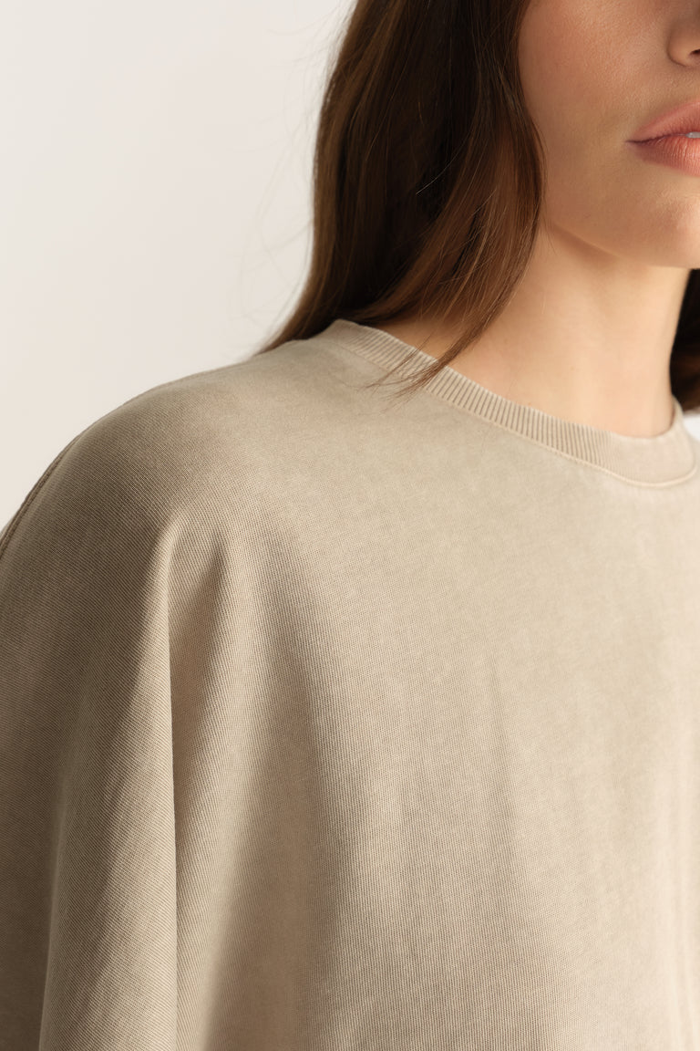 Close up of a woman wearing a taupe relaxed fit crew neck tee with batwing sleeves