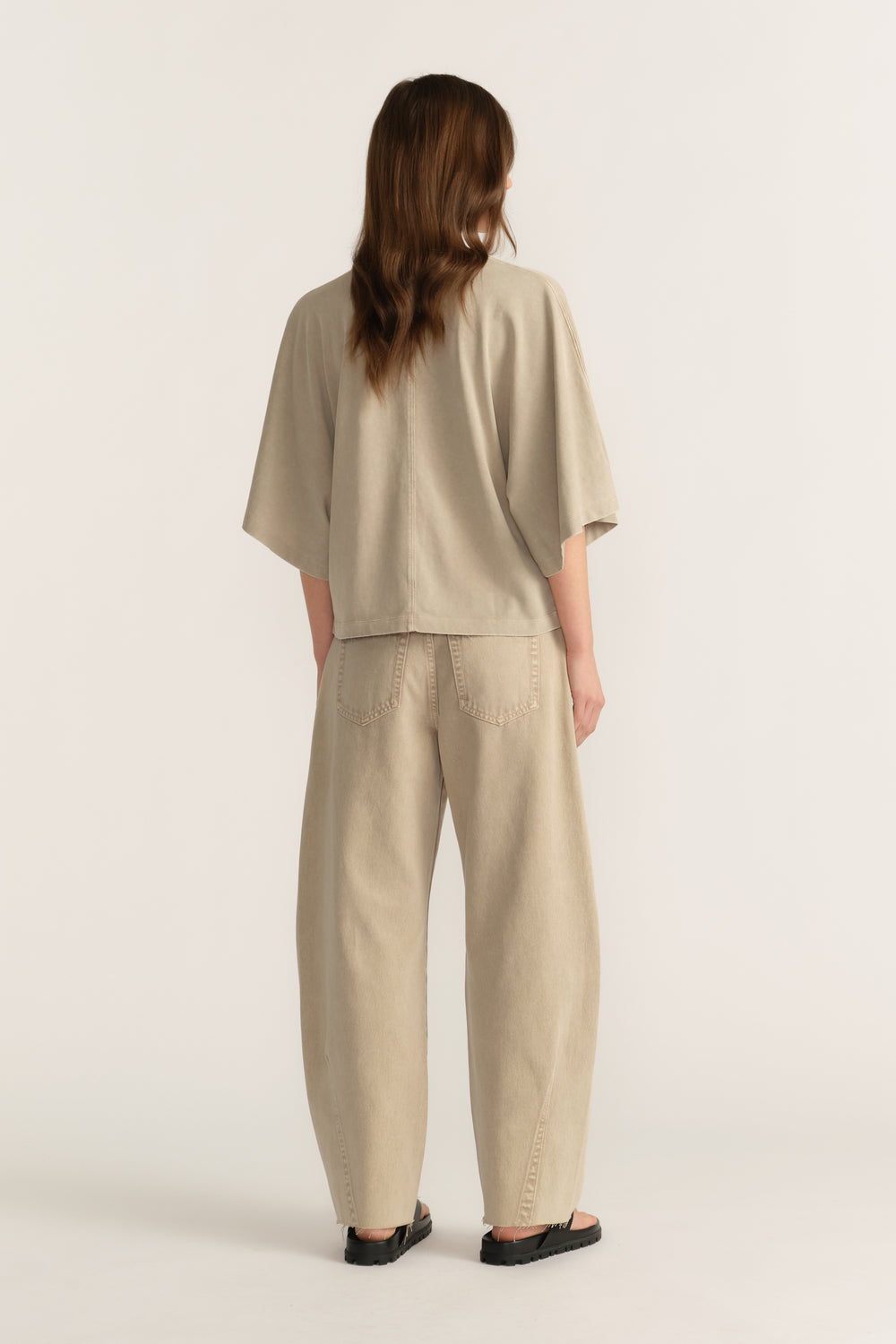 Back view of a woman wearing a relaxed taupe tee with matching wide-leg pants and black shoes