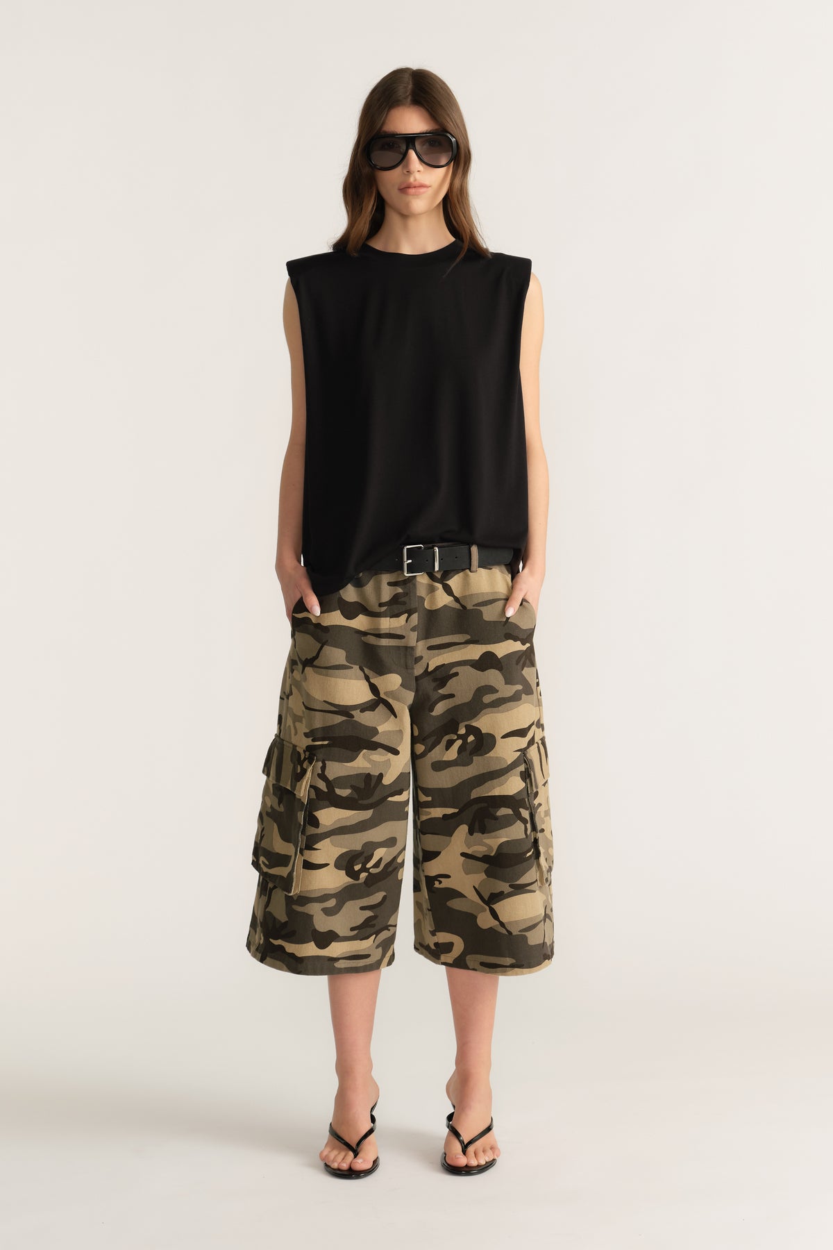 Woman wearing a black sleeveless top and camouflage cargo shorts with sunglasses