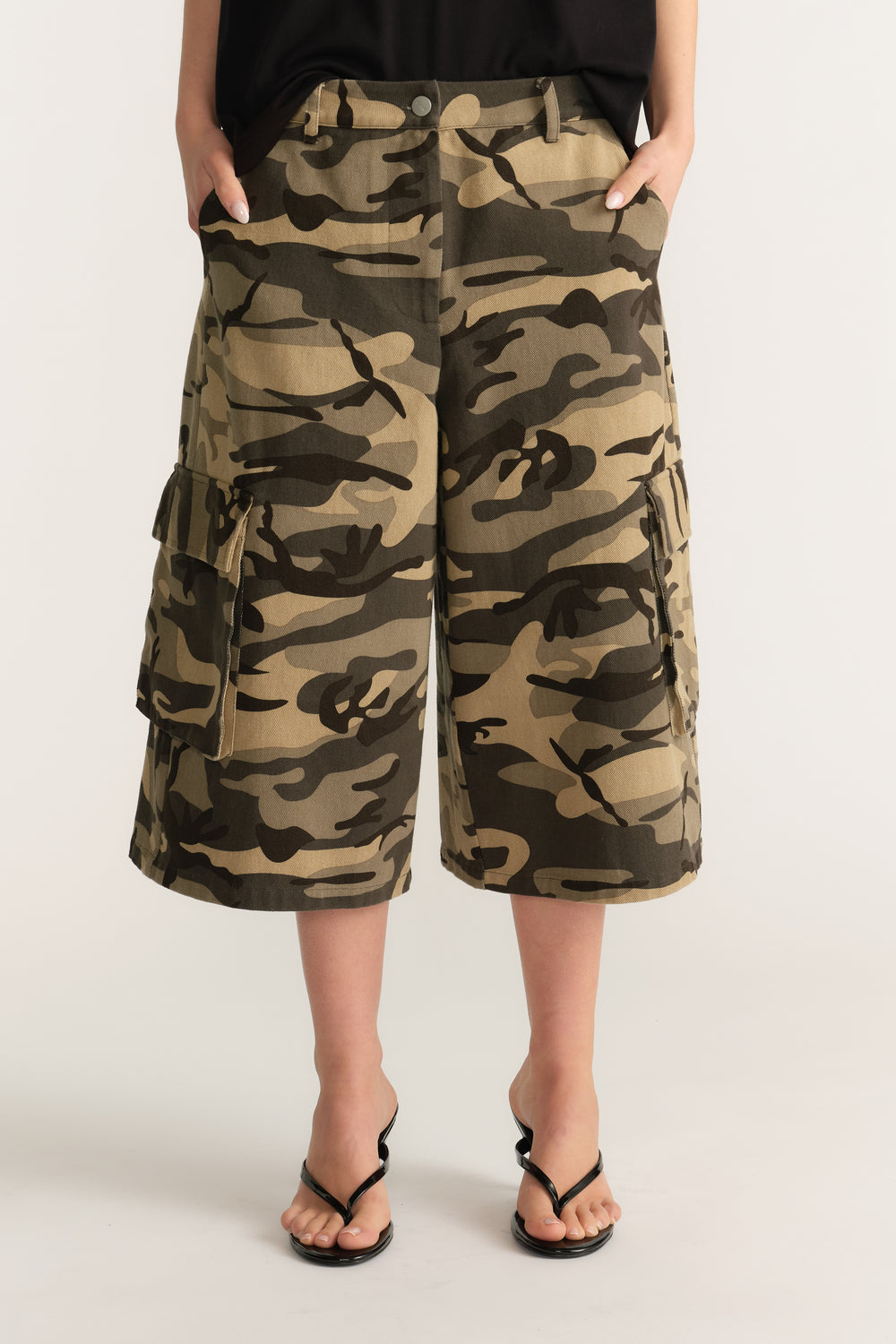 Woman wearing camo cargo shorts with a black top and black sandals