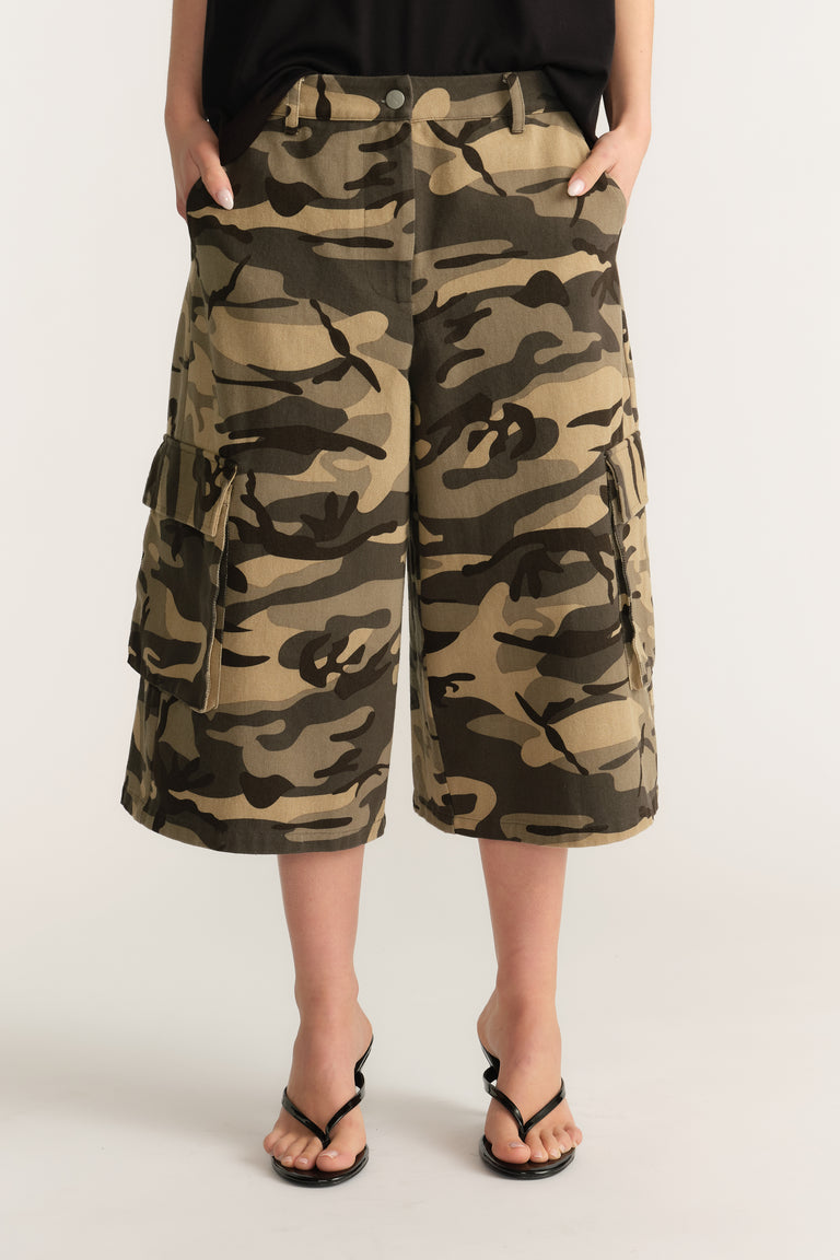 Woman wearing camo cargo shorts with a black top and black sandals