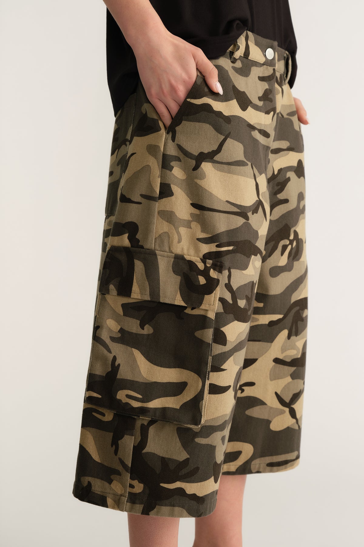 Woman wearing camouflage cargo shorts with wide legs and utility pockets