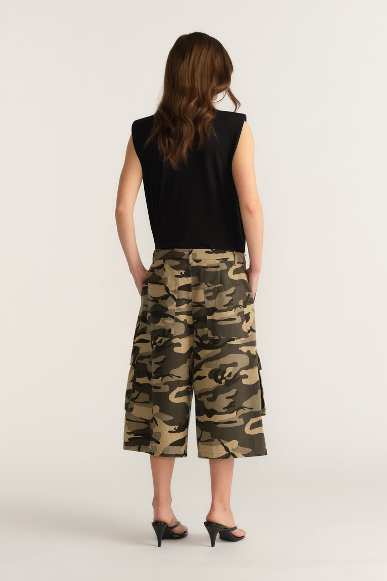 Back view of a woman wearing a black sleeveless top and camouflage wide leg cargo shorts with heels