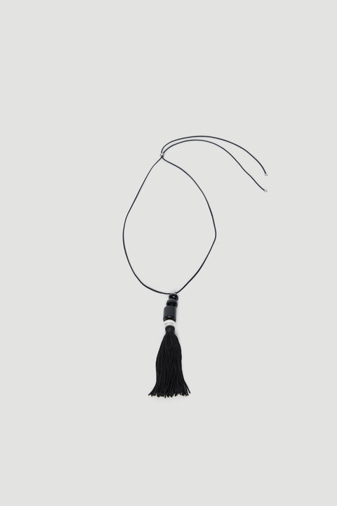 Black cord necklace with beaded pendant and tassel drop on a light background