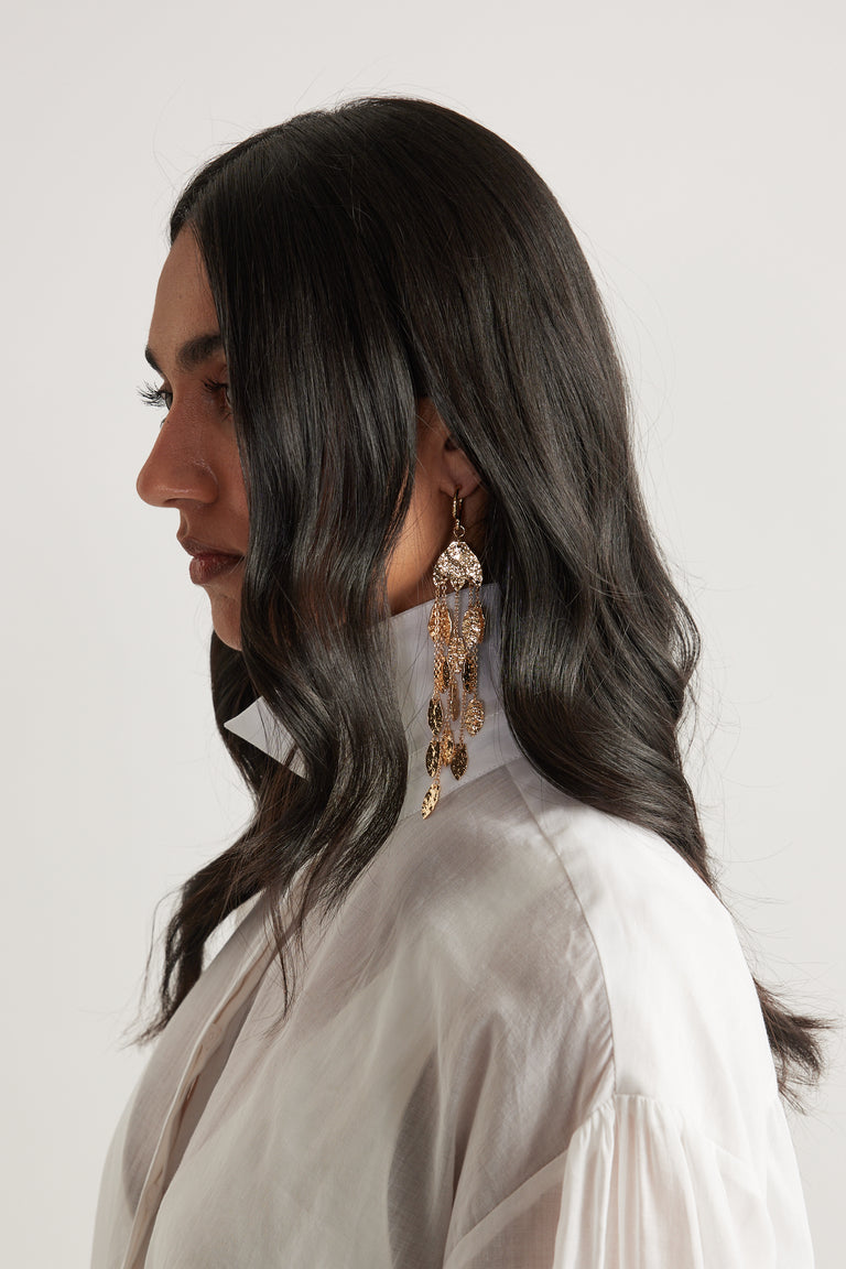 Woman wearing lightweight tiered gold leaf earrings with a hammered finish