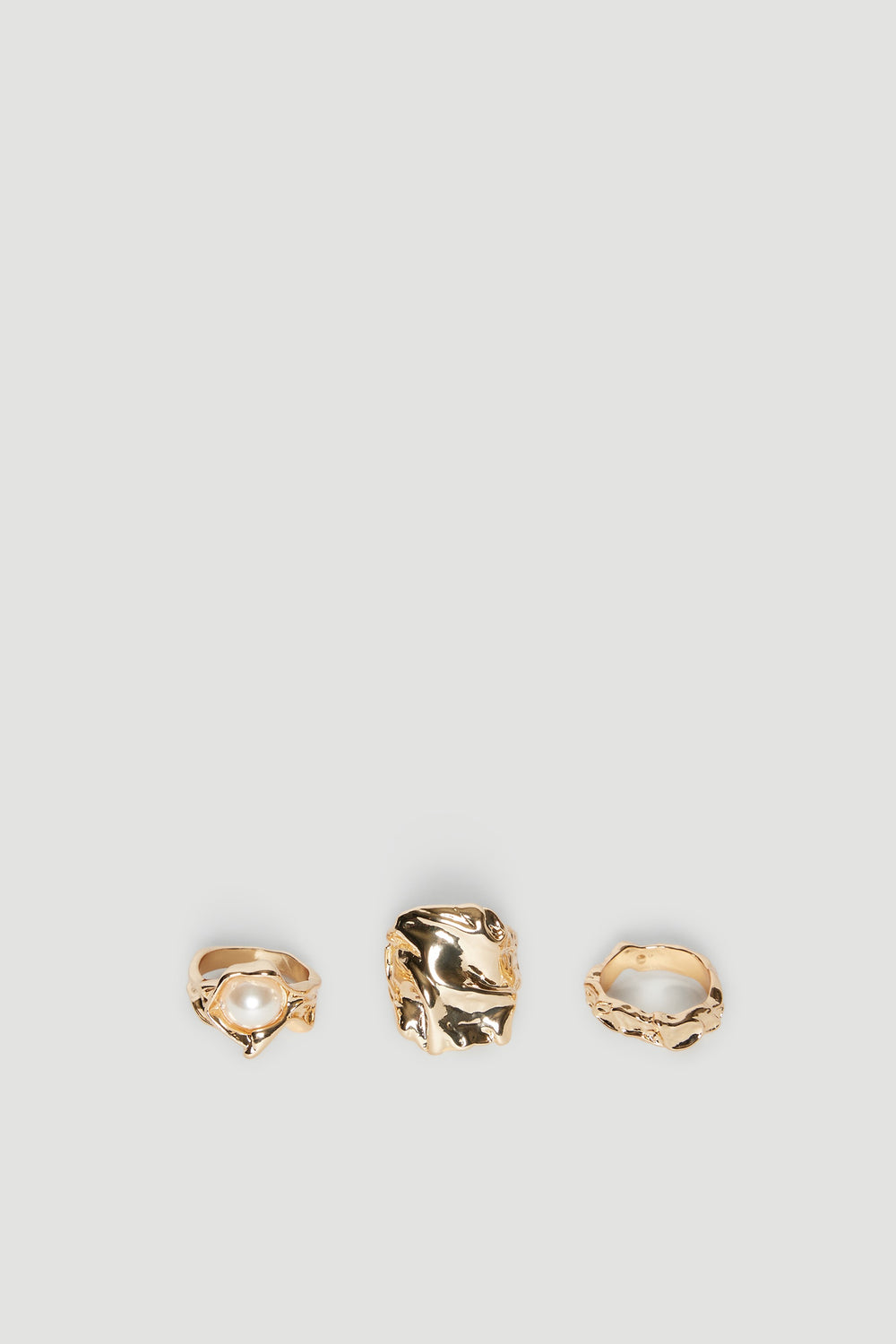 Three gold stackable rings with irregular shapes, including one with a pearl accent