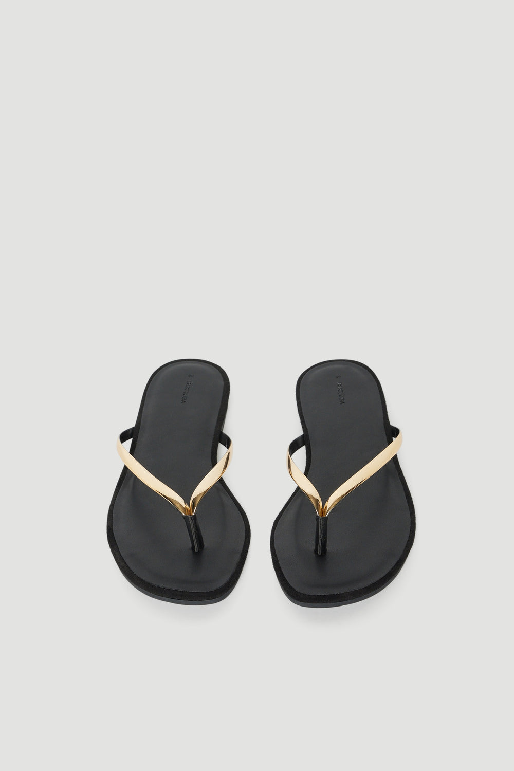 Pair of black thong sandals with thin high shine gold straps and padded footbeds