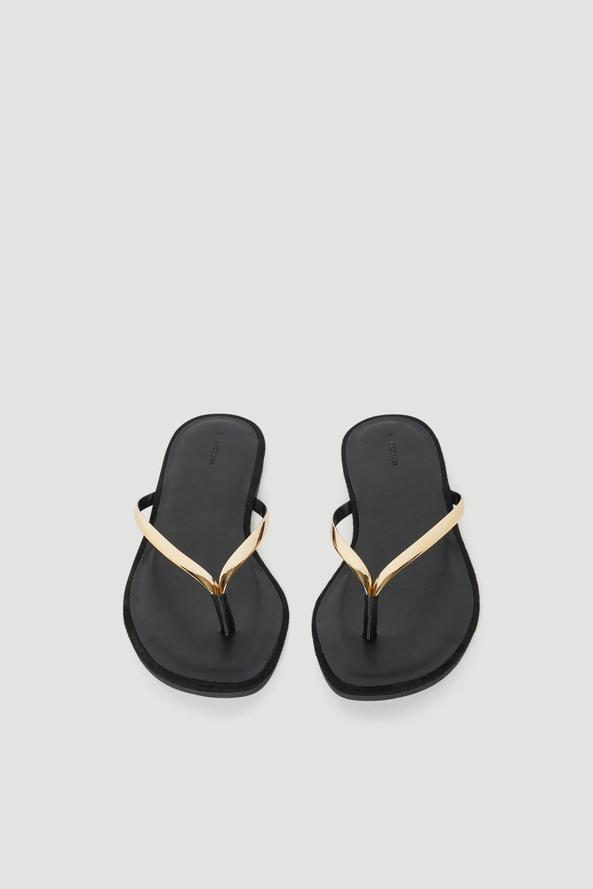 Pair of black thong sandals with thin high shine gold straps and padded footbeds