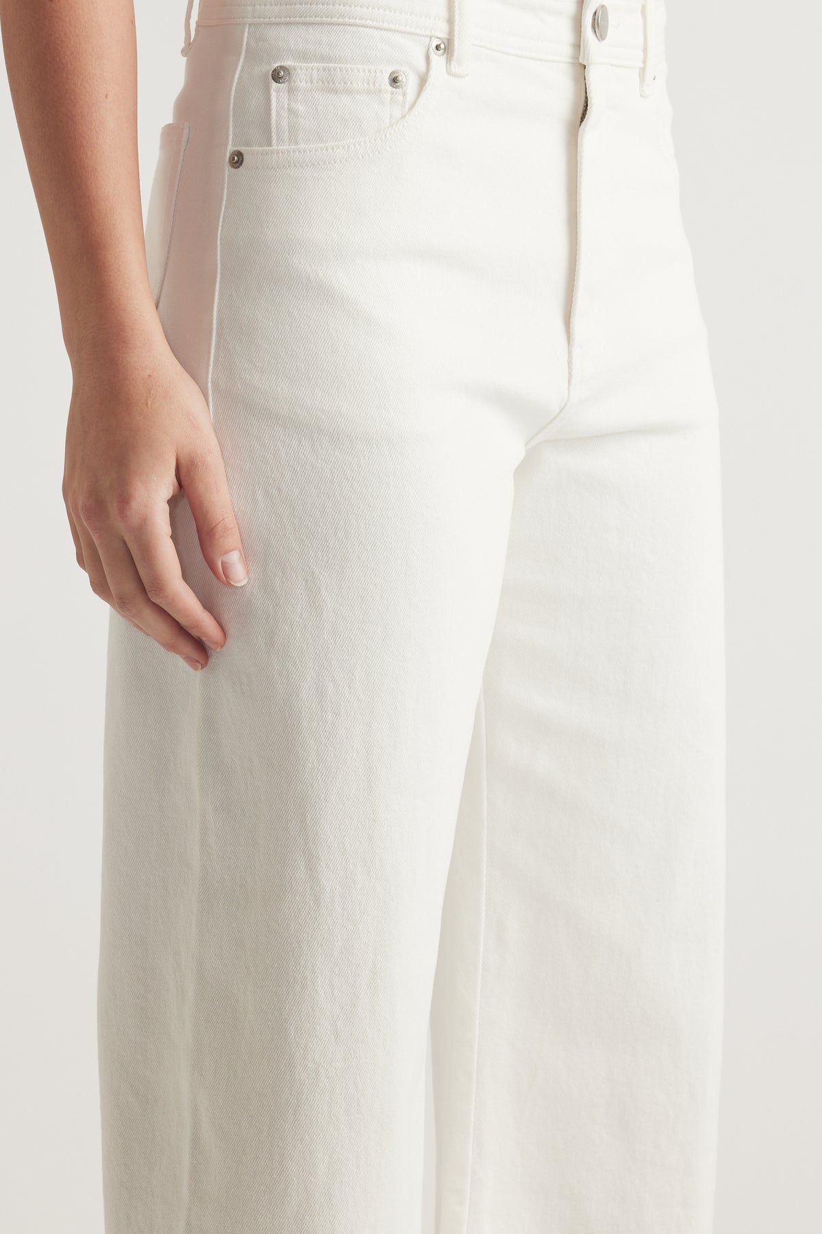 Close-up of white high rise wide leg jeans with front pockets and zip fly