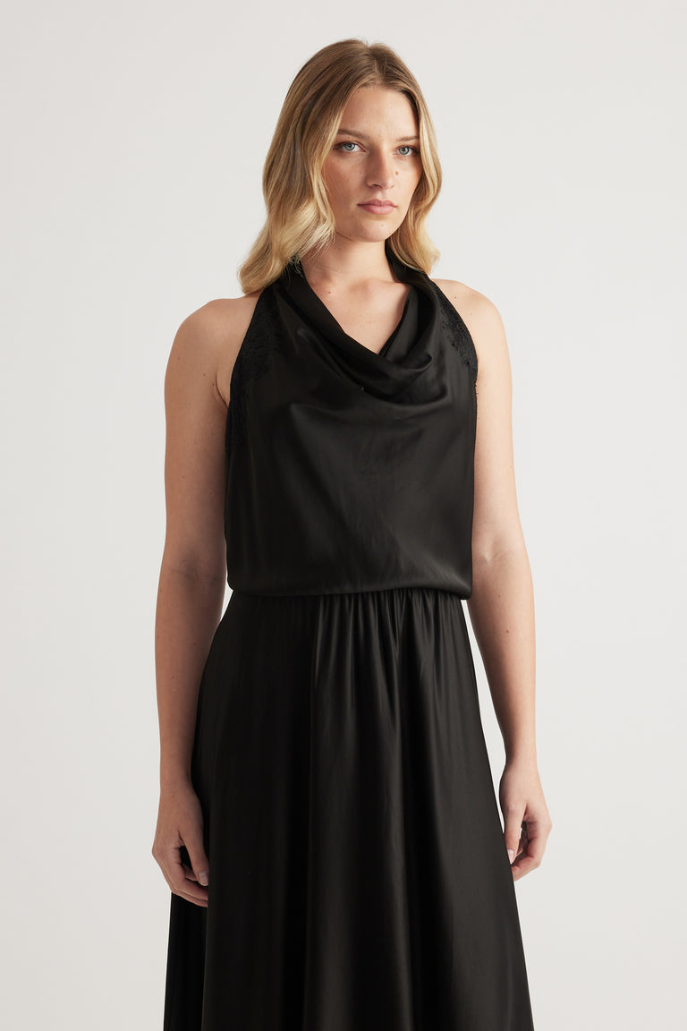 Woman wearing a black sleeveless halter midi dress with a draped neckline and flowing skirt