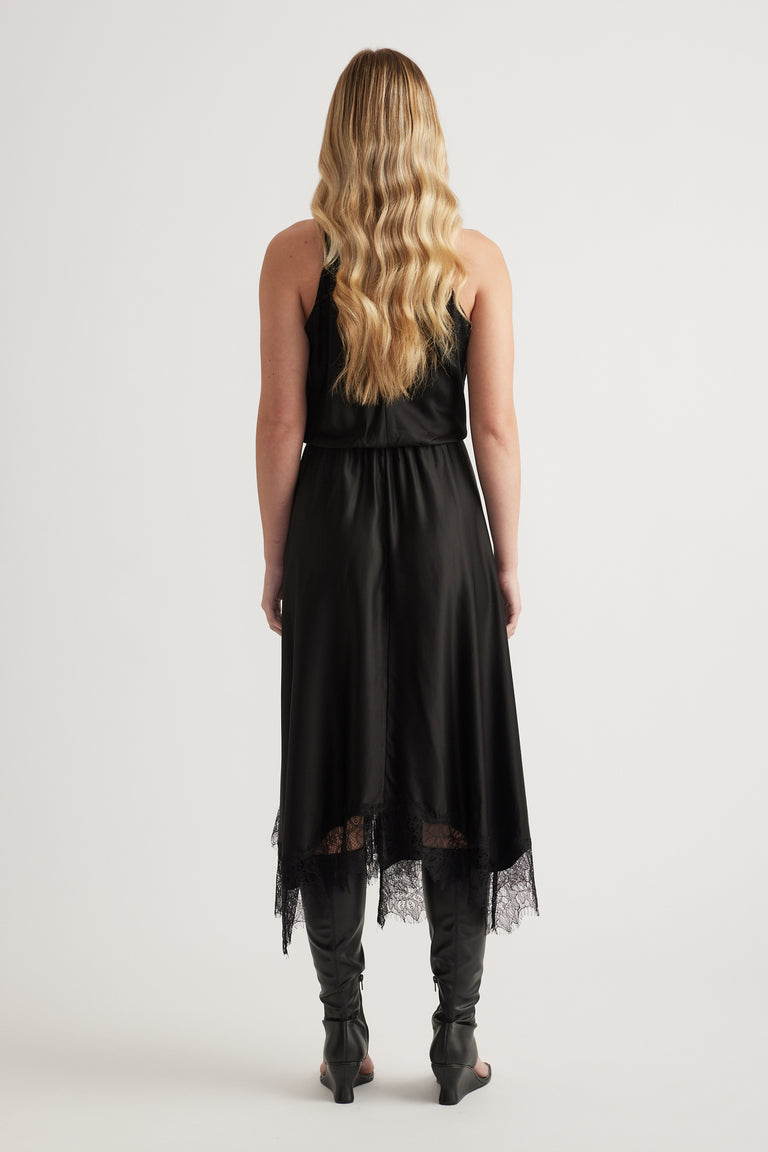 Back view of a woman in a black halter midi dress with lace hem and black boots