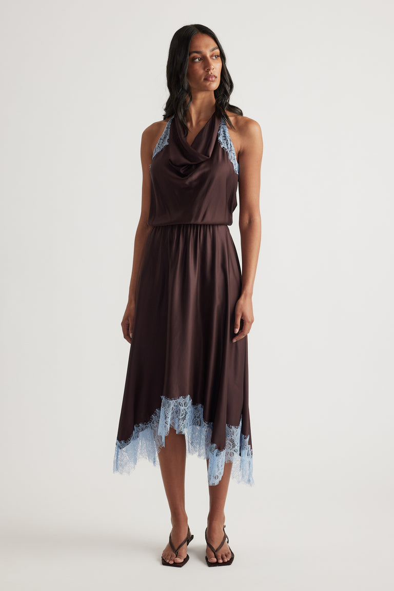 Model wearing a chocolate brown halter midi dress with blue lace trim and black strappy sandals