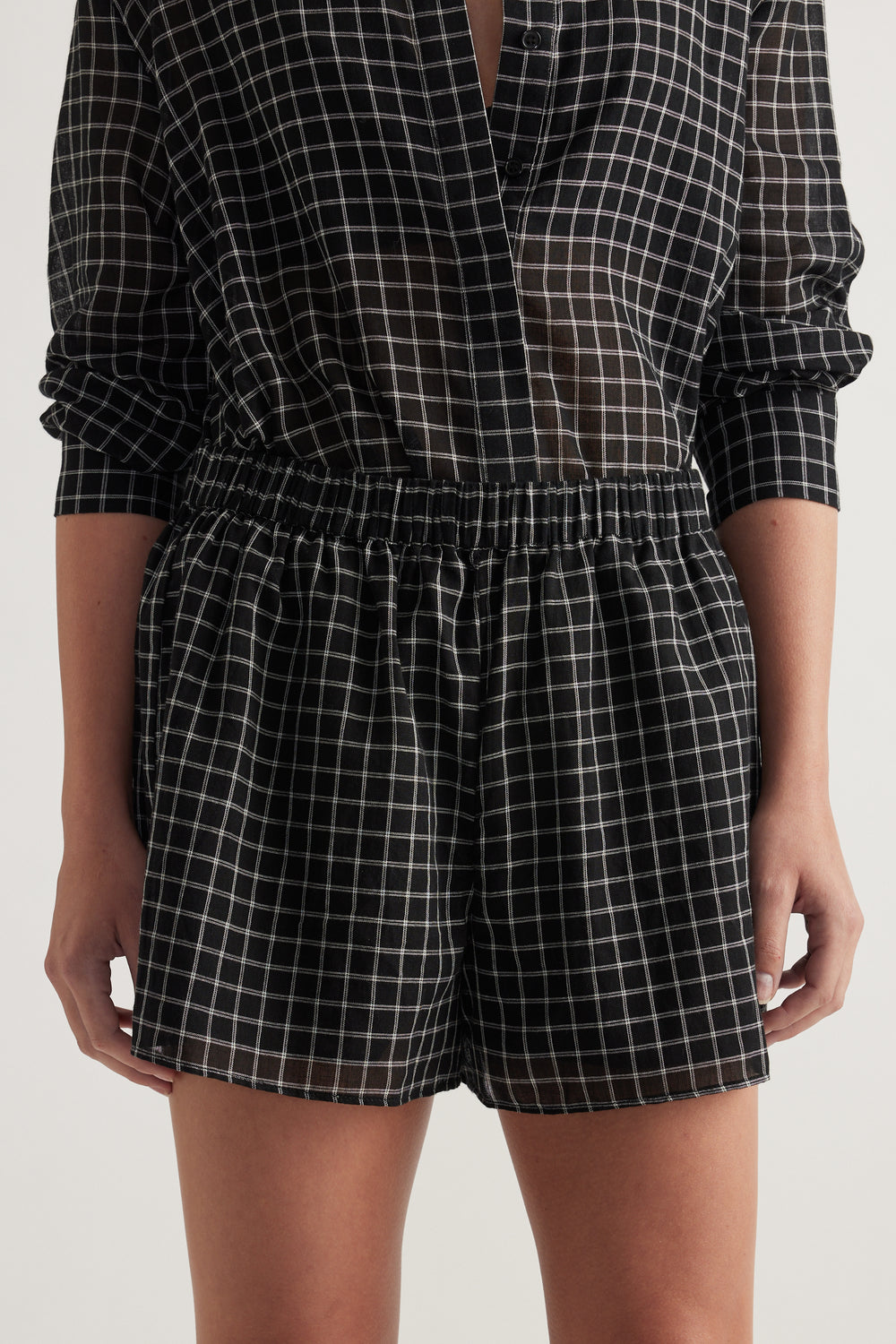 Woman wearing black and white check shorts with an elastic waist and matching long sleeve shirt