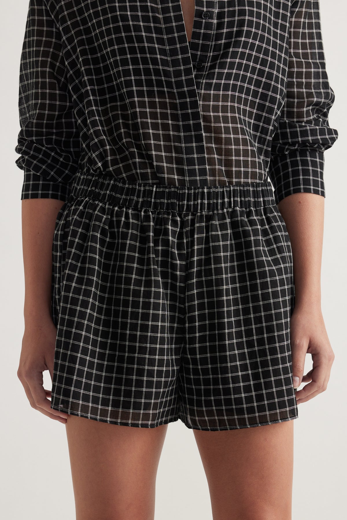 Woman wearing black and white check shorts with an elastic waist and matching long sleeve shirt