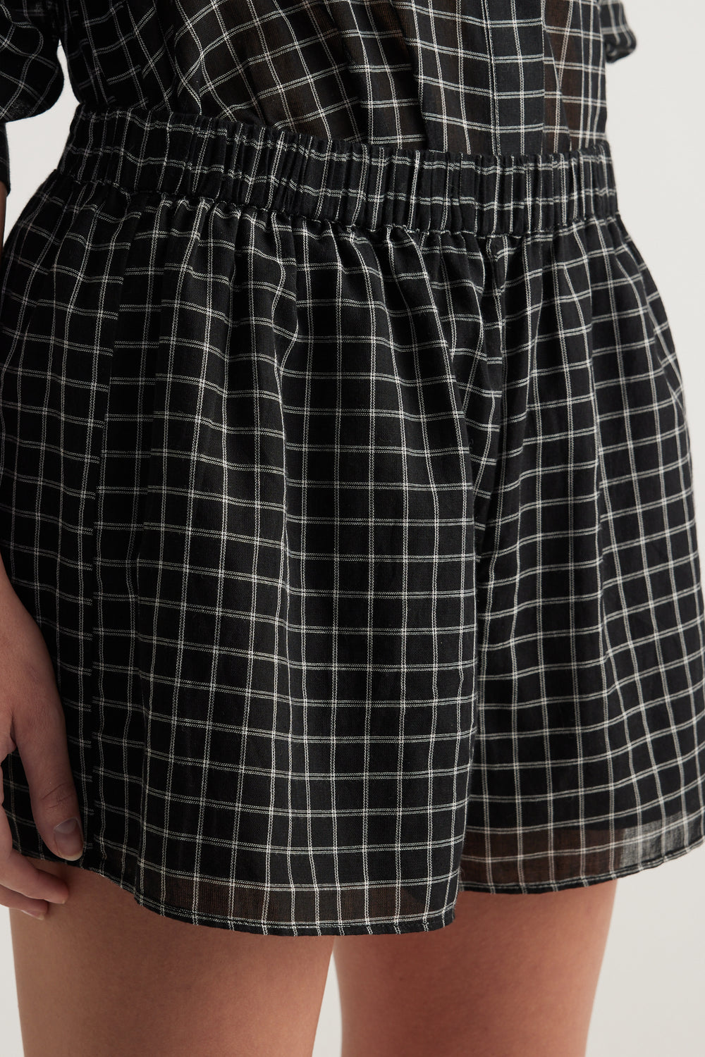 Model wearing black checked shorts with an elasticated waist and wide leg fit