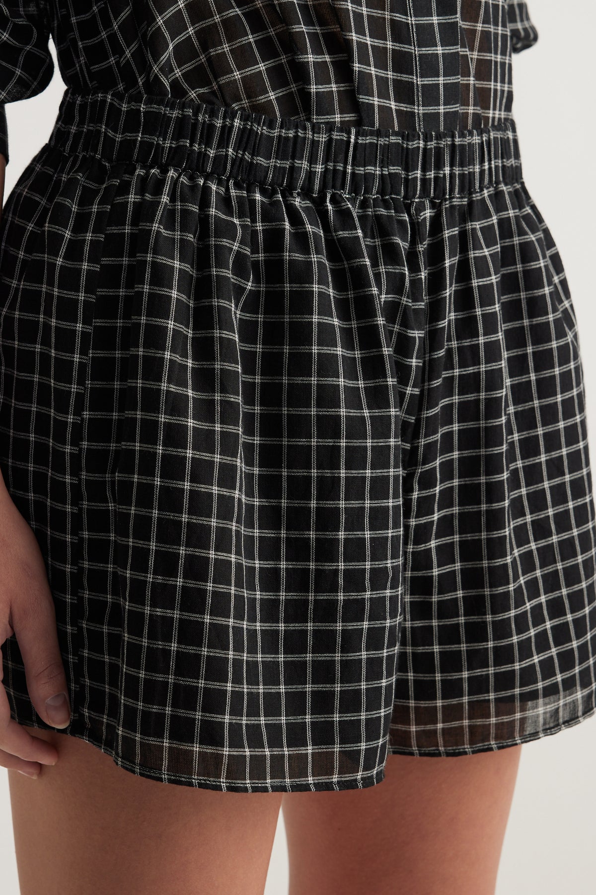 Model wearing black checked shorts with an elasticated waist and wide leg fit