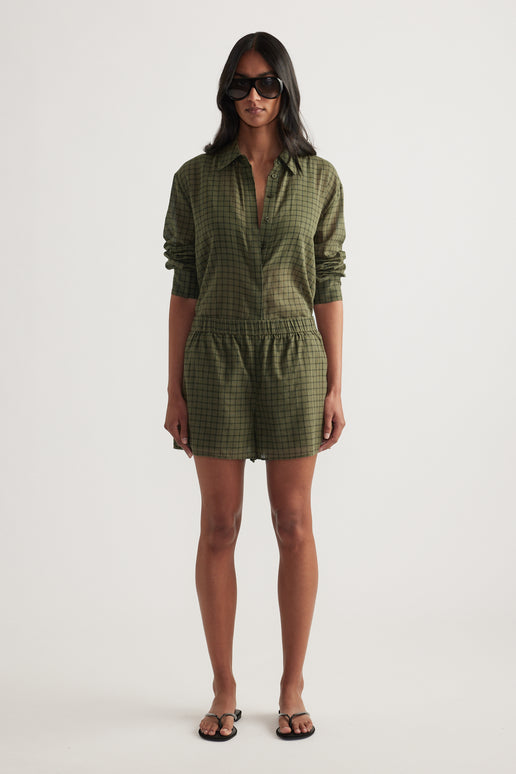 Woman wearing an olive green checked shirt and matching wide-leg shorts with sandals