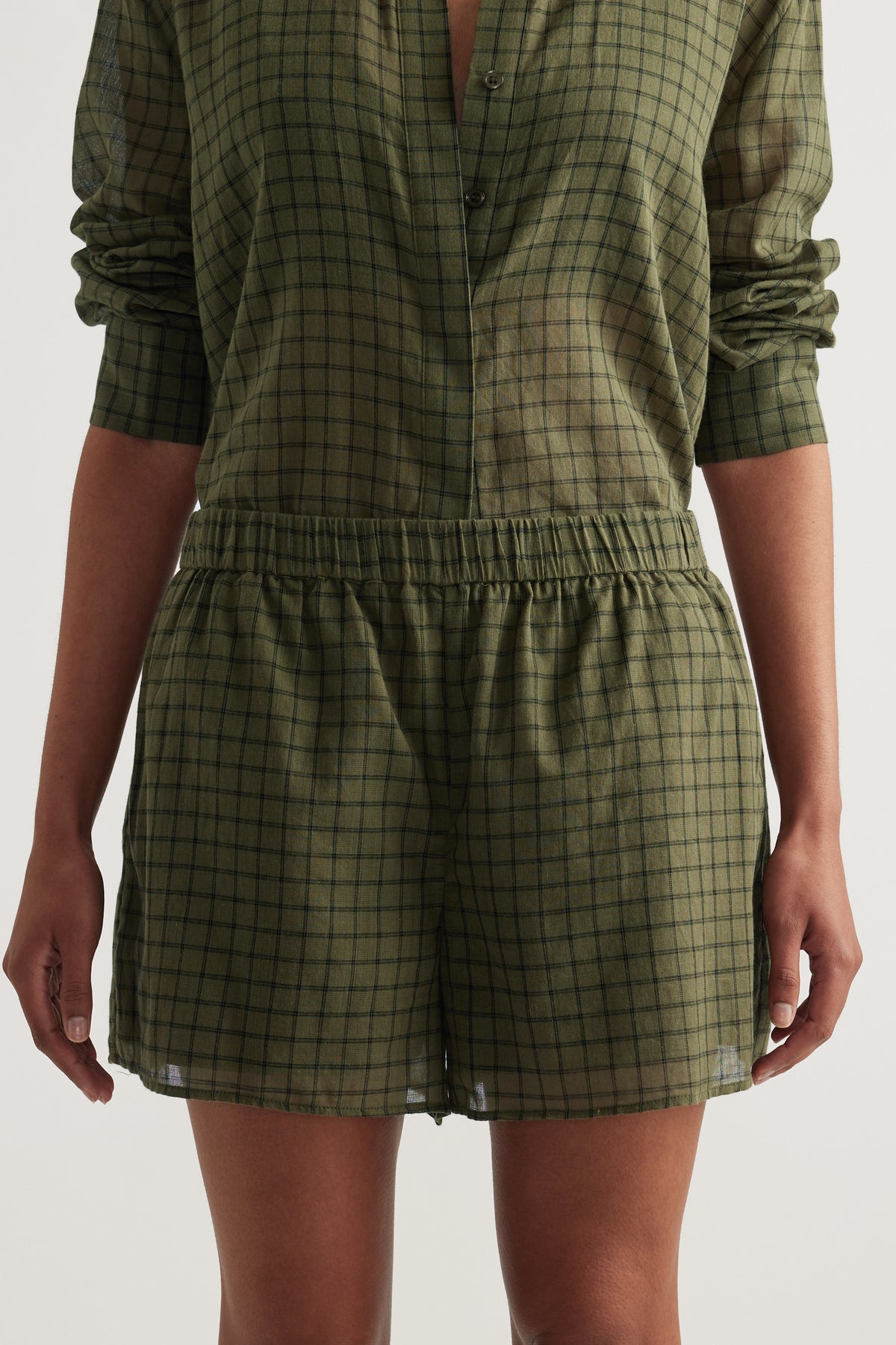 Model wearing an olive green checked shirt with matching elastic waist shorts