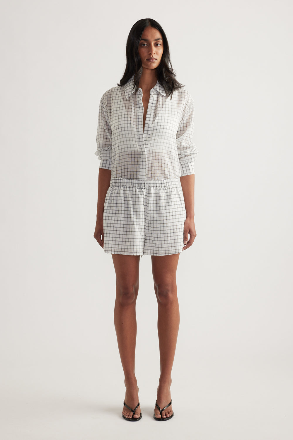 Model wearing a checked blouse with matching wide-leg shorts and strappy sandals