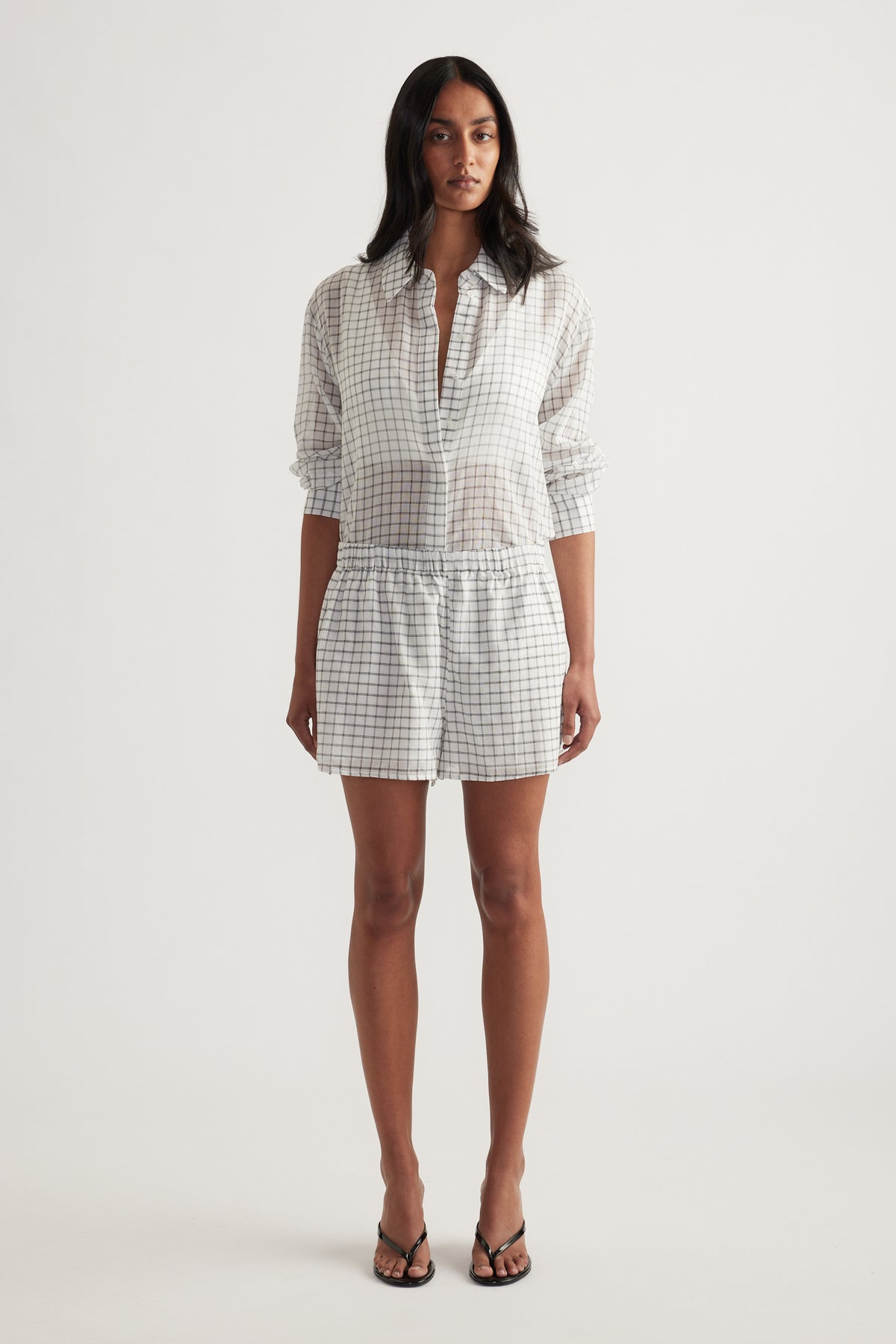 Model wearing a checked blouse with matching wide-leg shorts and strappy sandals