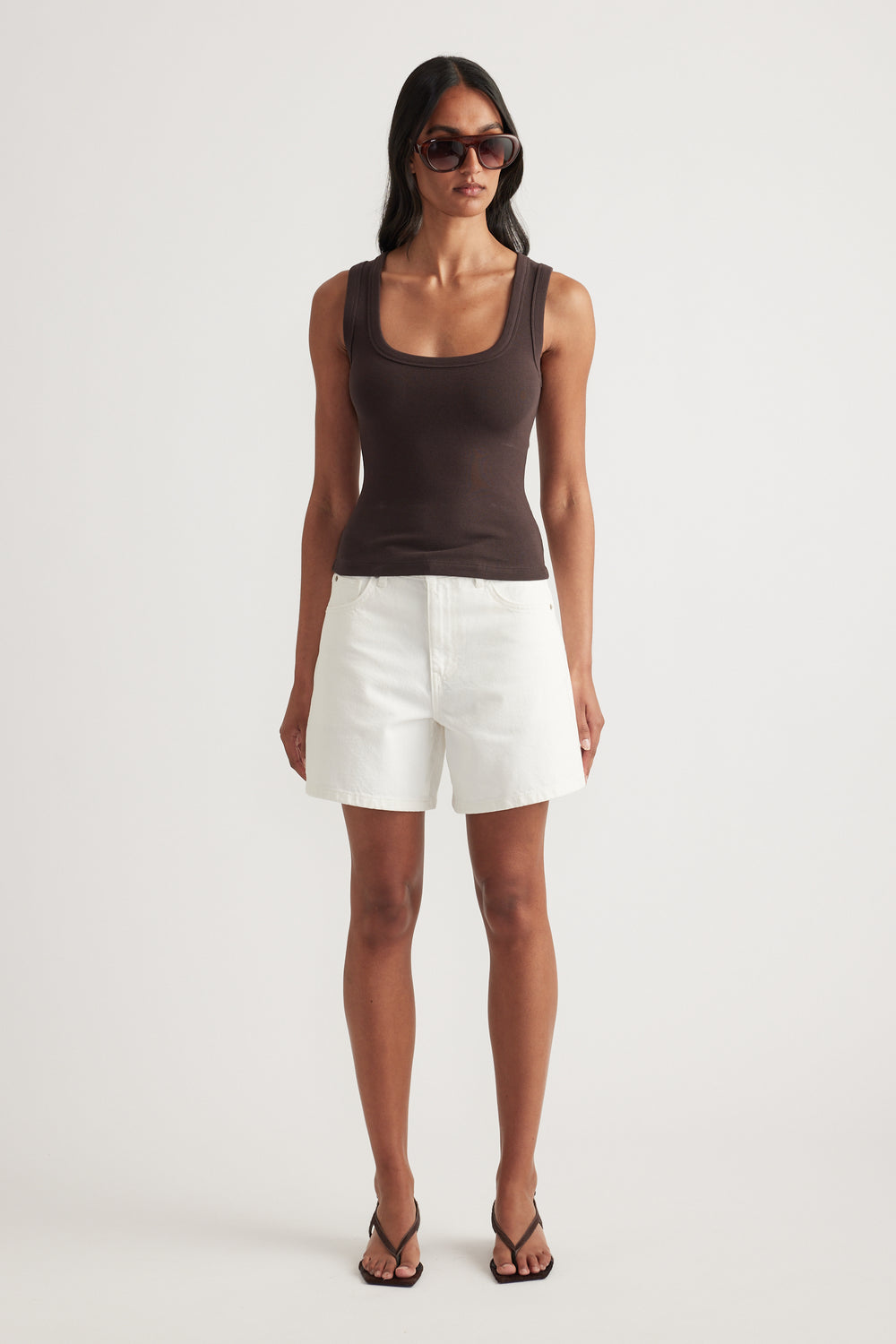 Woman wearing a brown fitted ribbed scoop neck tank with white shorts and sandals