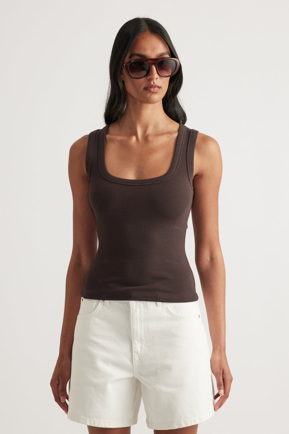 Woman wearing a brown fitted rib tank with a scoop neckline and white shorts