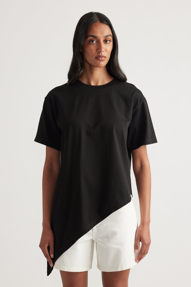 Woman wearing a black crew neck tee with an asymmetric hem and white shorts