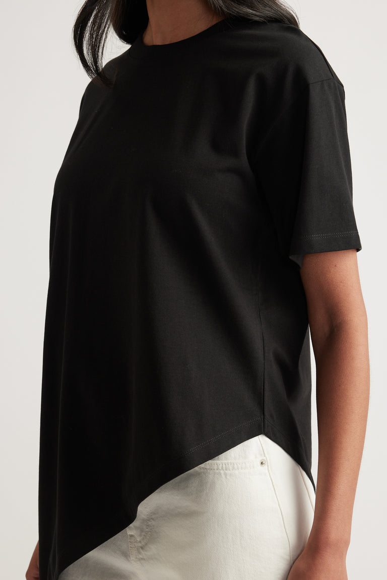 Woman wearing a black crew neck tee with an asymmetric hem and white pants