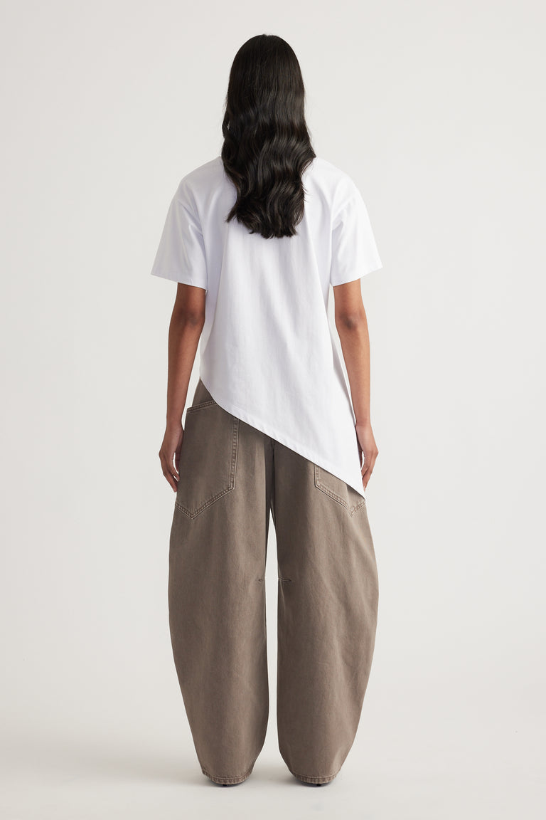 Back view of a woman wearing a white asymmetric hem tee with taupe wide leg pants