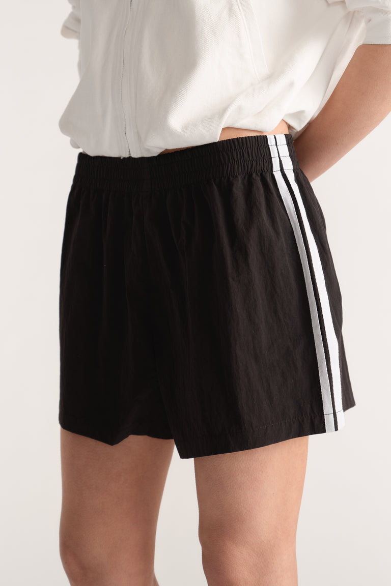 Black elastic waist shorts with white side stripes worn with a white top