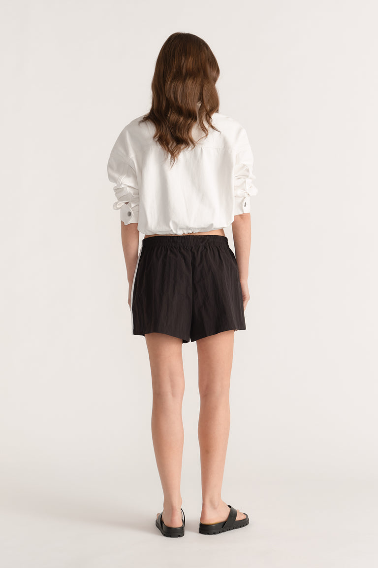Model wearing black elastic waist shorts with a white blouse and black sandals