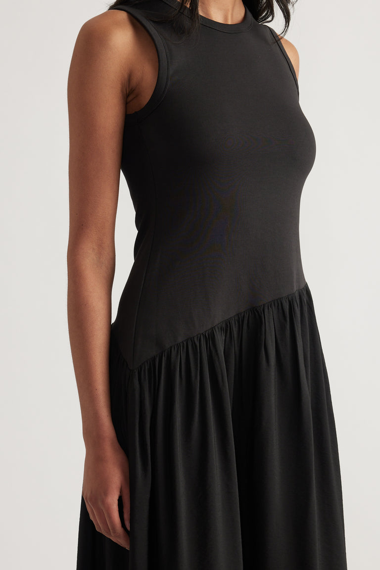 Black sleeveless dress with a crew neckline, fitted bodice and gathered skirt with an asymmetric waist seam