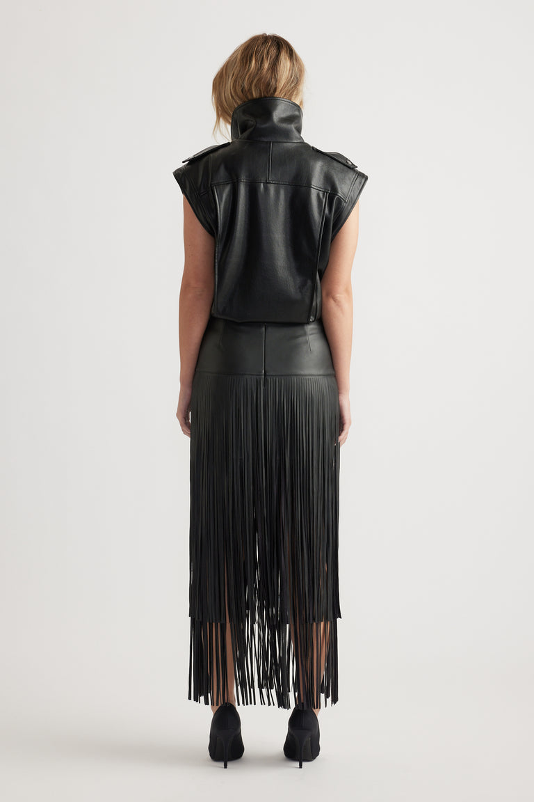 Rear view of woman wearing fitted high-waist black skirt with tiered fringe detailing and sleeveless cropped top