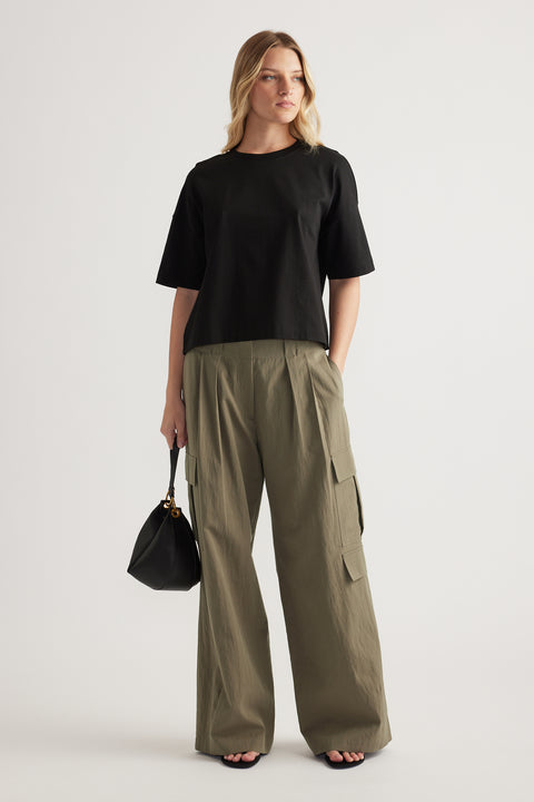 Woman wearing a black cropped boxy tee with olive cargo pants and carrying a black handbag