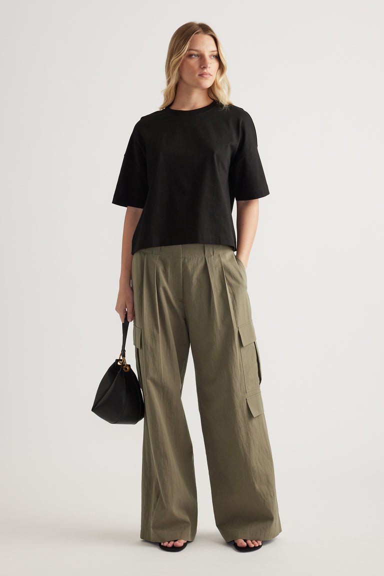 Woman wearing a black cropped boxy tee with olive cargo pants and carrying a black handbag