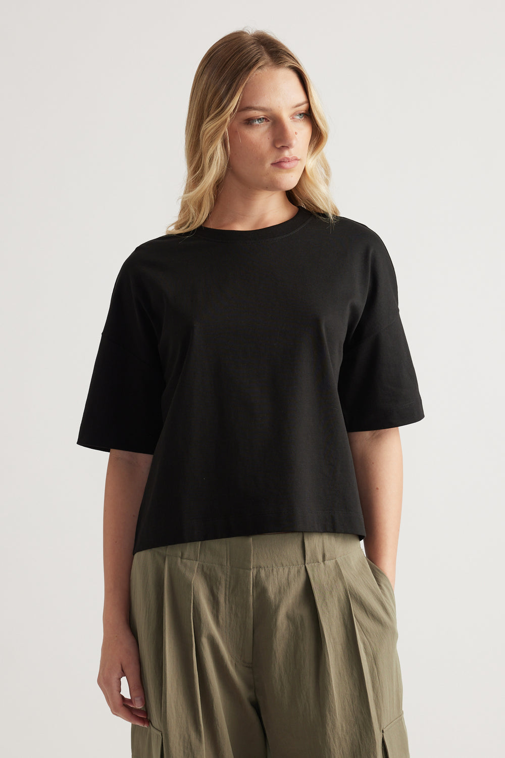 Woman wearing a black cropped boxy tee with olive wide leg pants