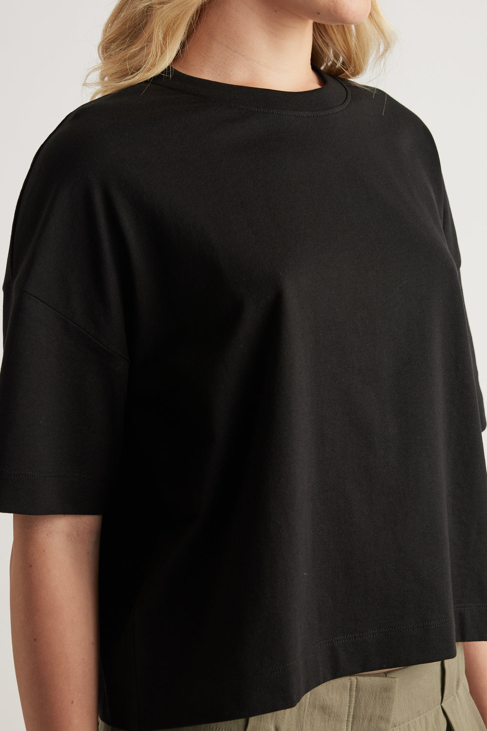 Woman wearing a black cropped boxy crew neck tee with short sleeves