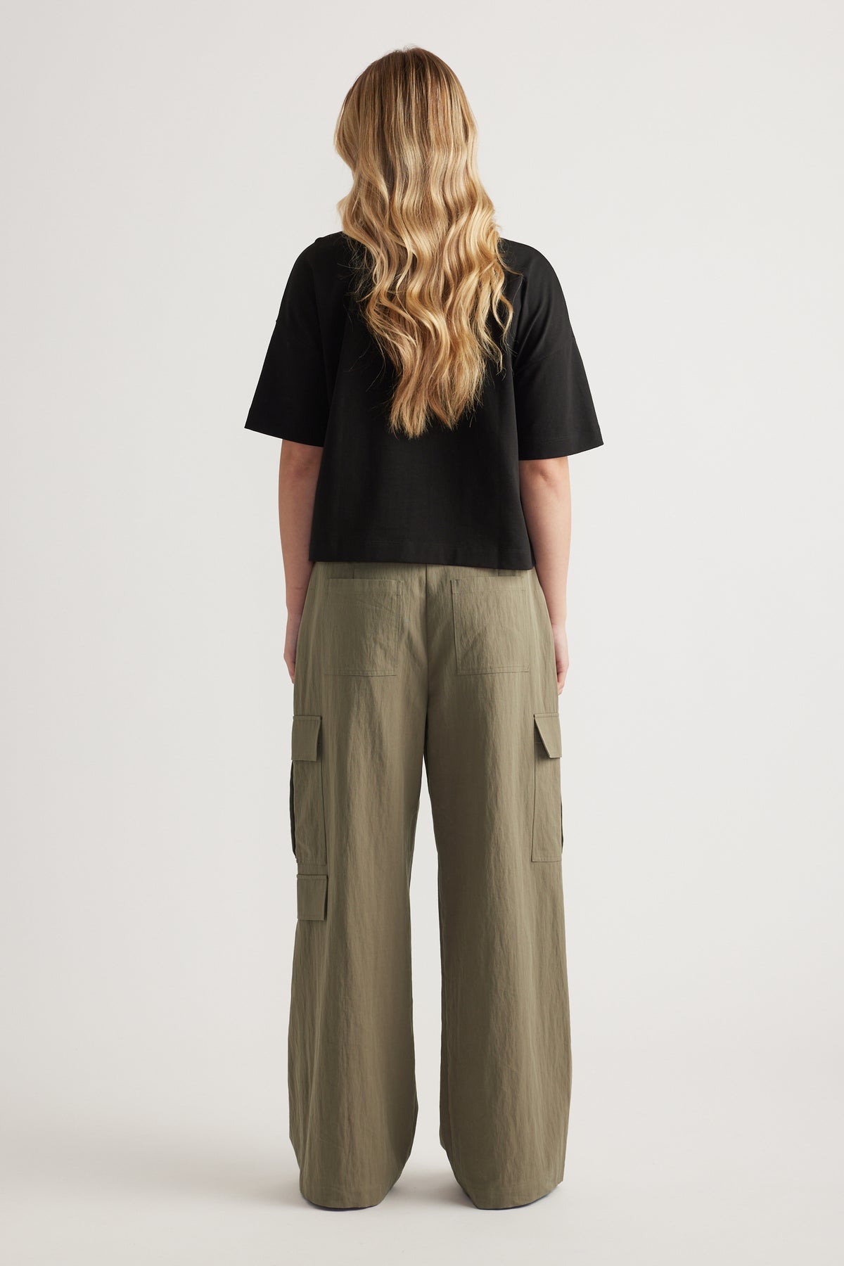 Back view of a woman wearing a black cropped tee and olive green cargo pants