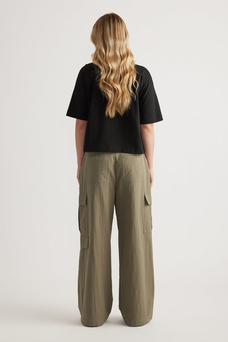 Back view of a woman wearing a black cropped tee and olive green cargo pants