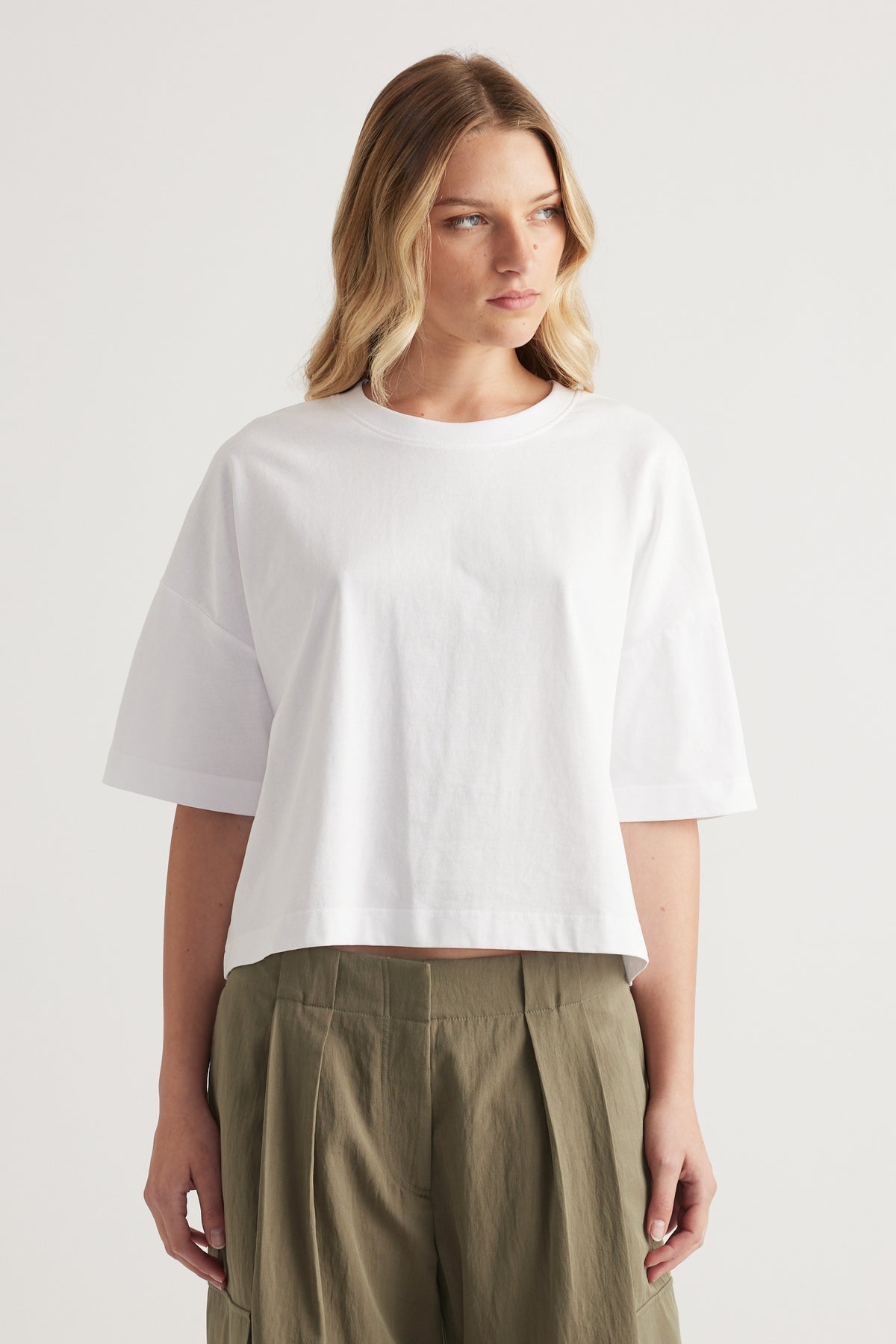 Woman wearing a white cropped boxy tee with olive green pants