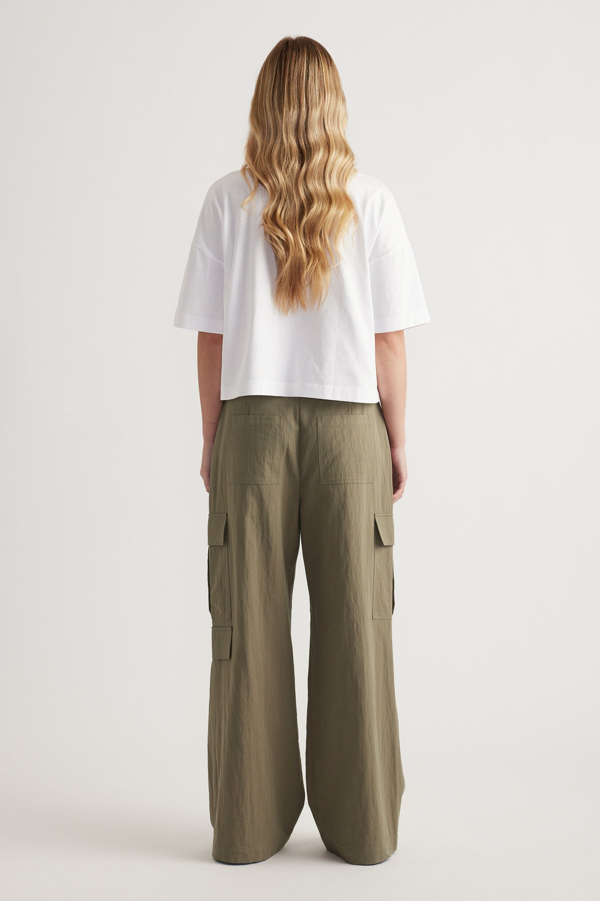 Back view of a woman wearing a white cropped boxy tee and olive wide leg cargo pants