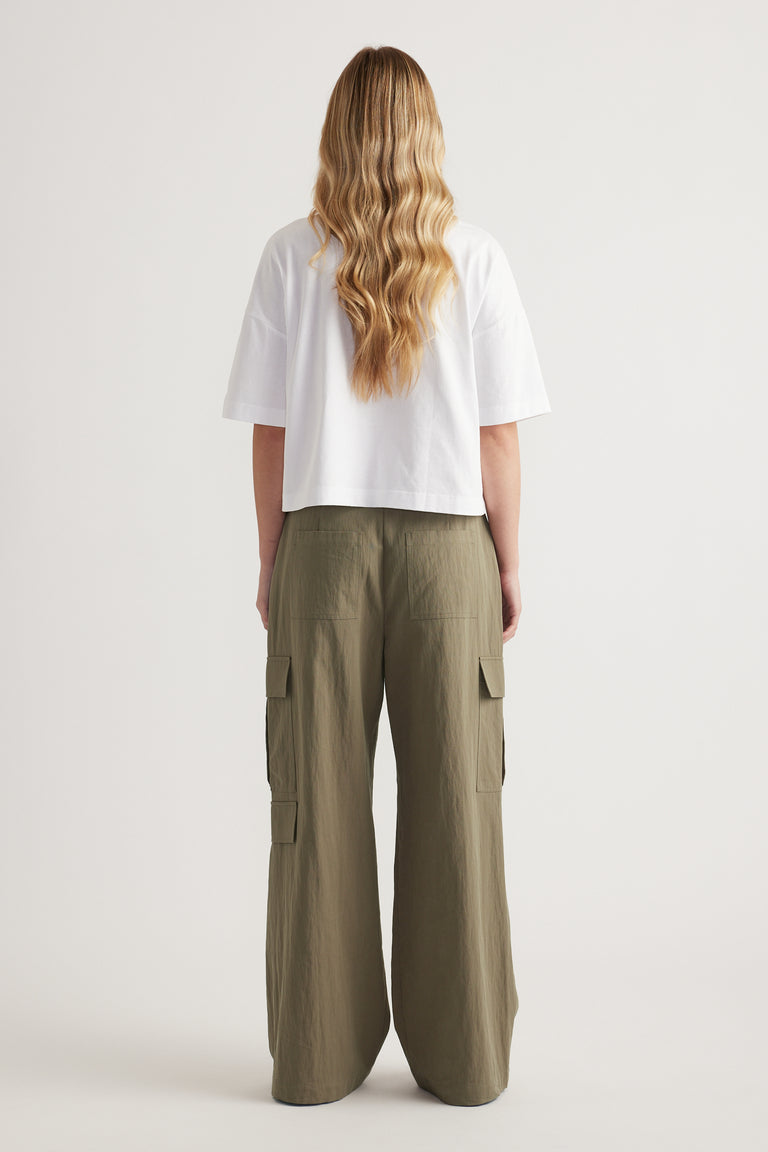 Back view of a woman wearing a white cropped boxy tee and olive wide leg cargo pants