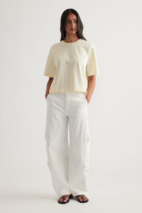 Woman wearing a cream cropped tee with white cargo pants and black sandals