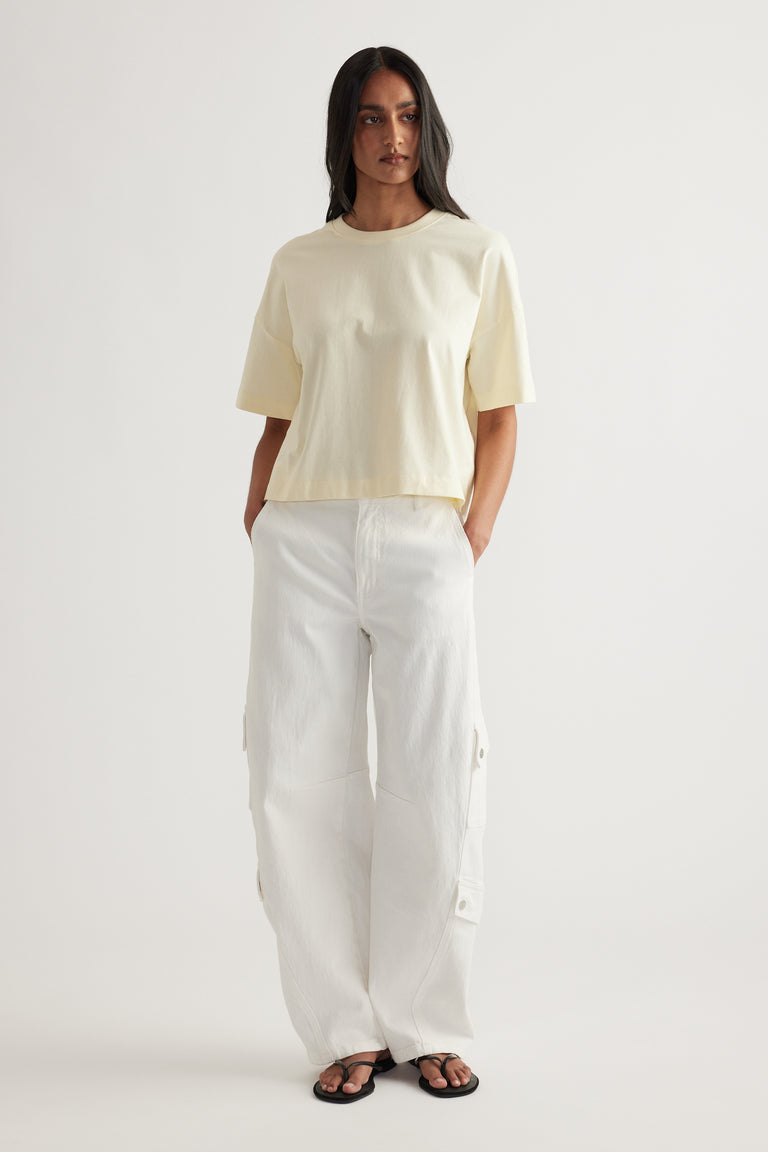 Woman wearing a cream cropped tee with white cargo pants and black sandals