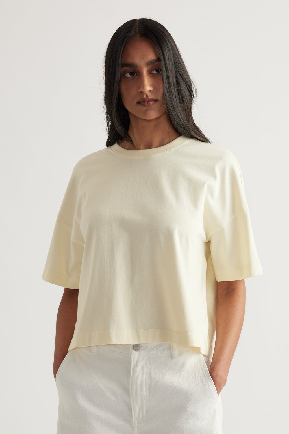 Woman wearing an off-white cropped boxy tee with short sleeves and a crew neck
