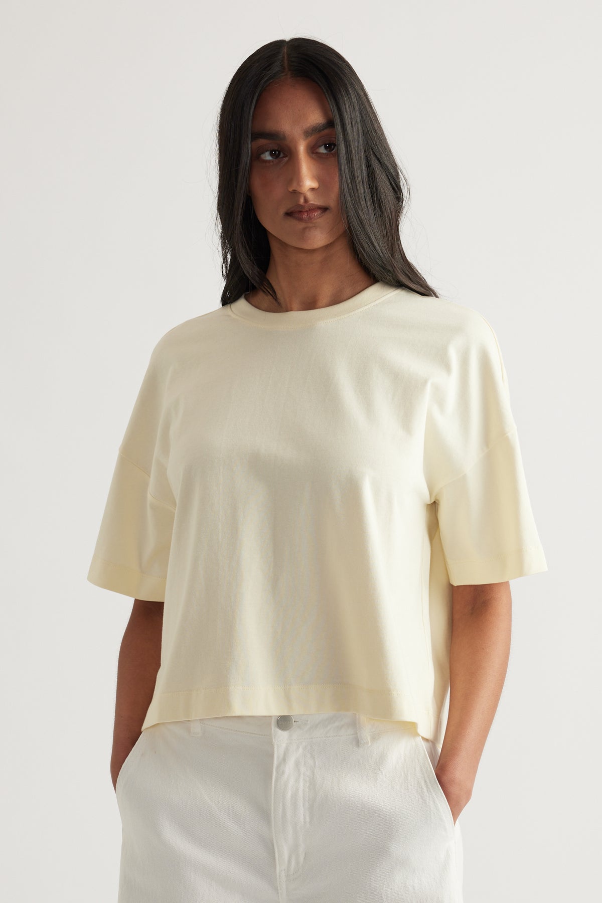 Woman wearing an off-white cropped boxy tee with short sleeves and a crew neck